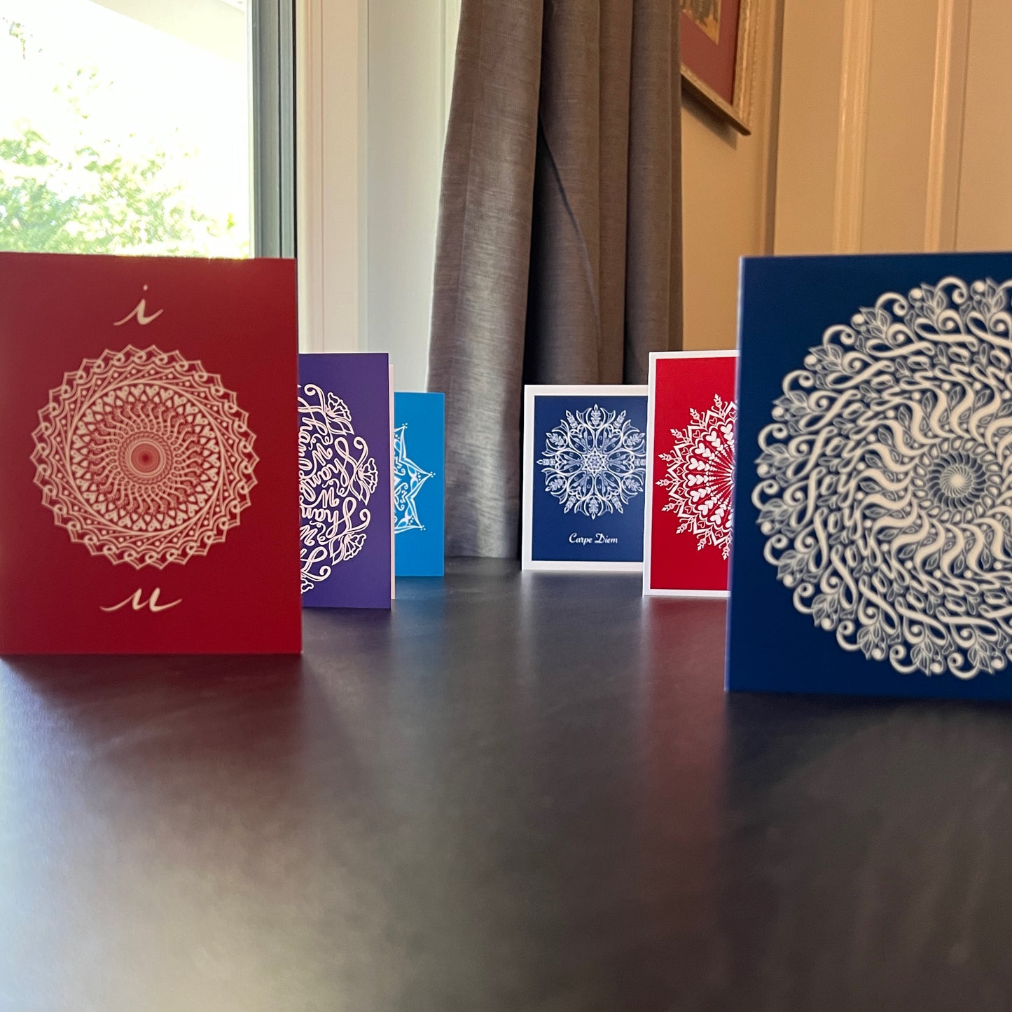 This is a picture of our Hidden Word Mandala greeting card line.  In each of these cards, here is a hidden message. The cards are displayed on a disk with a natural background.  All of these beautiful greeting cards are the art of Jennifer Knight of Newwingstudio.com